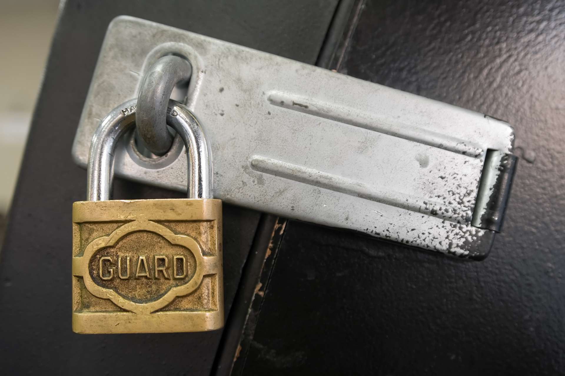 A worn brass padlock labeled GUARD secures a silver latch on black metal, illustrating proven controls for third-party cyber risk.