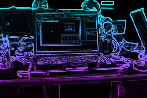 An open laptop with neon outlines shows a Cyber Risk Advisory dashboard, while two professionals work at computers amid tech equipment.