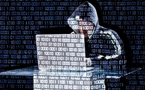 A person in a hoodie at a laptop under binary code highlights real cyber threats, underscoring the value of expert cyber risk analysis.